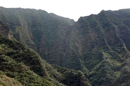 Objevují se Hanakoa Falls padající z vysokých zelených svahů.